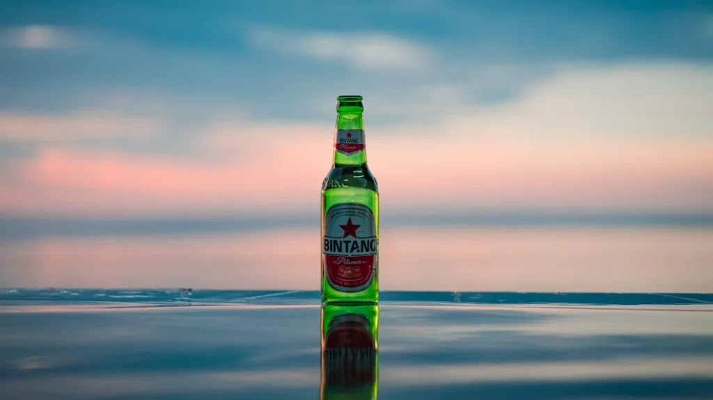 Botella de cerveza frente al mar al atardecer