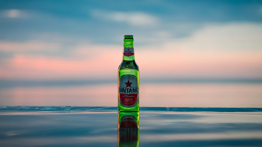 Botella de cerveza frente al mar al atardecer